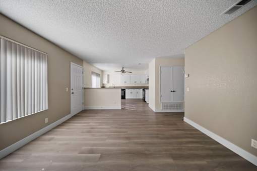 A spacious room with wooden flooring and white walls.