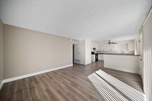 A room with wooden flooring and a striped rug in the middle.