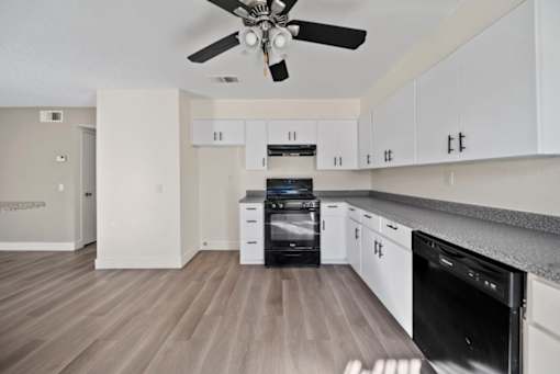 A modern kitchen with a black oven and white cabinets.