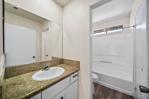A bathroom with a sink, mirror, and toilet.