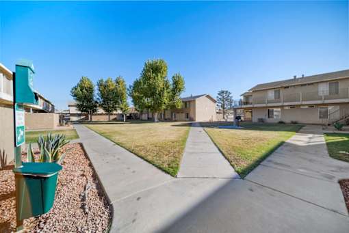 A sunny day in a residential area with apartment buildings and a sidewalk.