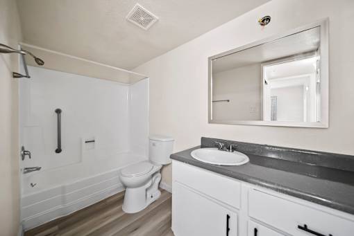 A white bathroom with a toilet, sink, and mirror.