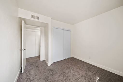 A room with a carpeted floor and a white door.