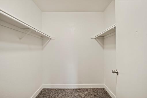 A small, empty room with a carpeted floor and a door.