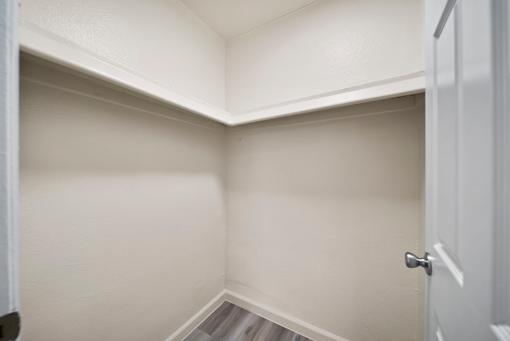 A white door is open to a small, empty room with white walls.
