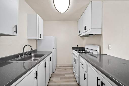 A kitchen with white cabinets and a stove top oven.