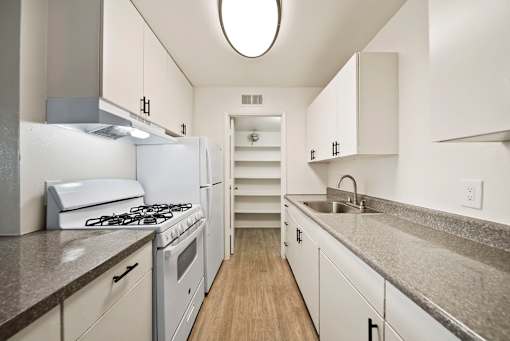 A kitchen with a white stove and cabinets.