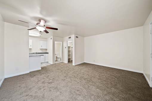 A room with a ceiling fan and carpeted floor.