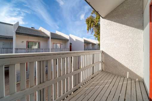 A balcony with wooden slats and a white wall.