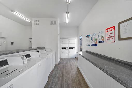A laundromat with washers and dryers and a notice on the wall.