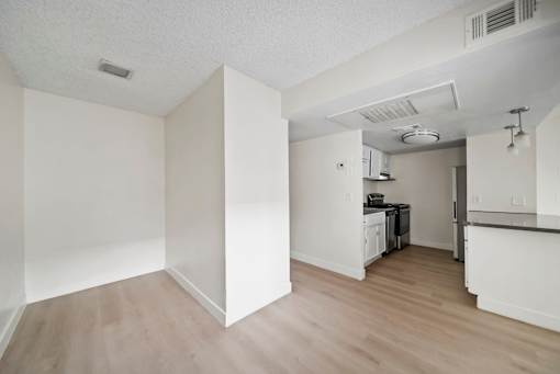 A kitchen area with white walls and wooden flooring.