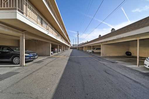 A long, narrow street with cars parked on both sides.