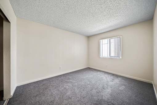 A room with a carpeted floor and a window with blinds.