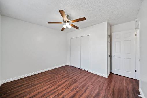 A room with a ceiling fan and wood flooring.