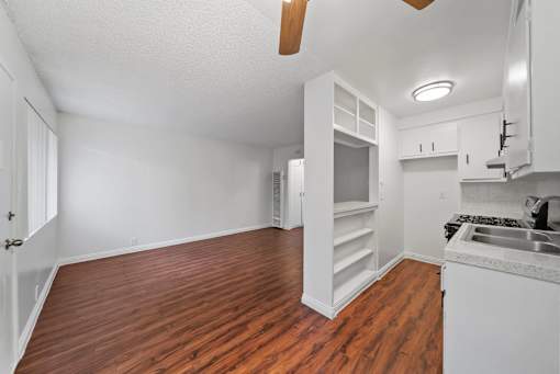 A kitchen with white cabinets and a wooden floor.