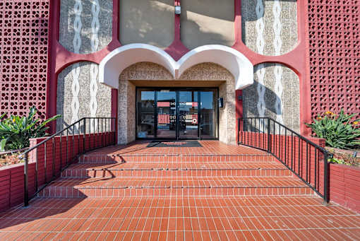 A red brick walkway leads to a building entrance.