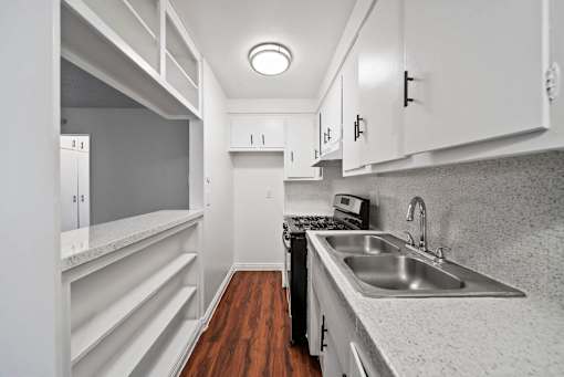 A kitchen with white cabinets and a wooden floor.