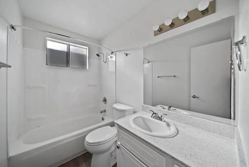 A white bathroom with a toilet, sink, and bathtub.