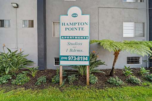 A sign for Hampton Pointe Apartments is in front of a building.