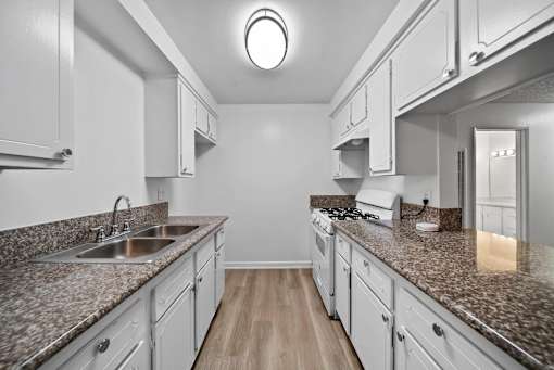 A kitchen with granite countertops and white cabinets.