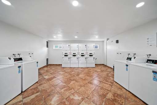 A laundry room with washing machines and dryers.