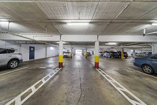 A parking garage with cars parked on both sides of the aisle.