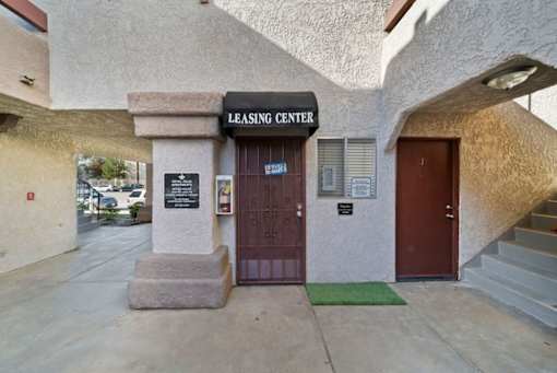The leasing center has a brown door and a green mat on the steps.