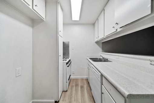 A kitchen with white cabinets and a black counter top.