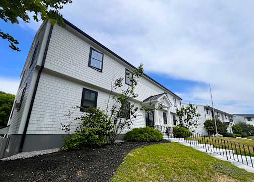 A white house with a black fence in front.