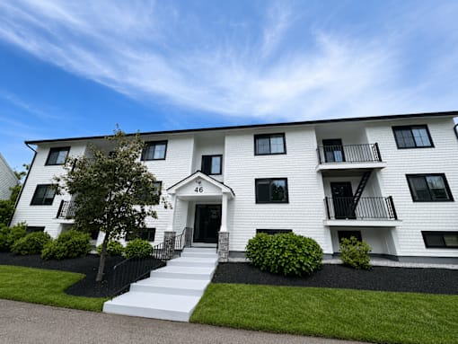A white two-story building with black railings and windows.