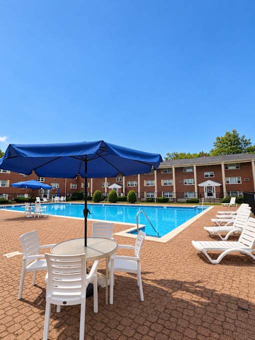 A blue umbrella is over a table with chairs around it.