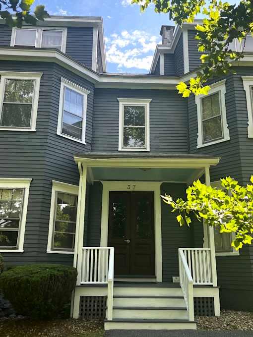 A house with a dark grey exterior and a white porch.