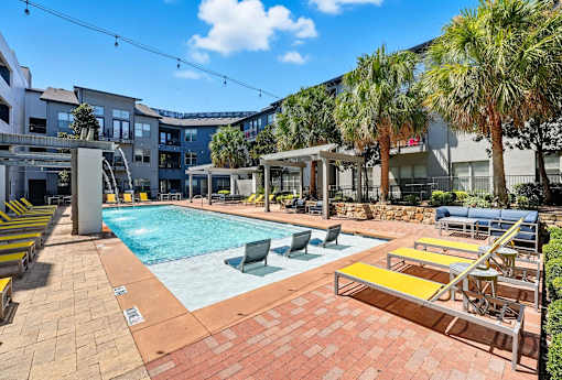 A pool area with sun loungers and palm trees at The Atlantic Highland Park, Texas, 75209