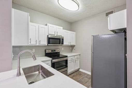 A kitchen with white cabinets and a stainless steel refrigerator at The Atlantic Canton Ridge, Georgia