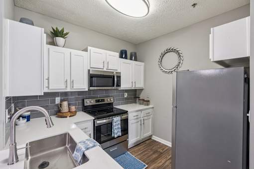 A kitchen with white cabinets and a grey refrigerator at The Atlantic Canton Ridge, Georgia