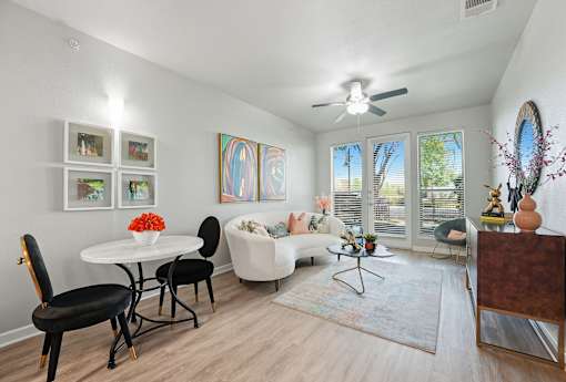 A living room with a white couch, a white table, and a painting on the wall at The Atlantic Highland Park, Texas, 75209