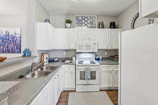 A white kitchen with a sink and a refrigerator.