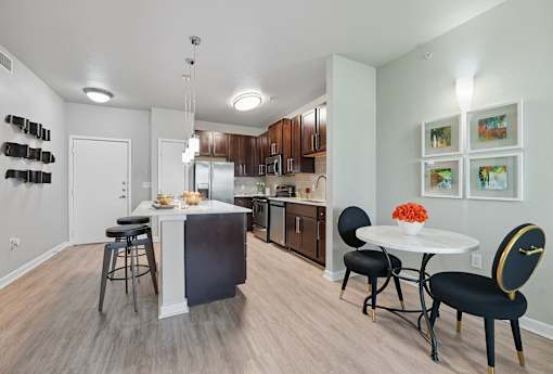 A kitchen with a white table and black chairs at The Atlantic Highland Park, Texas, 75209