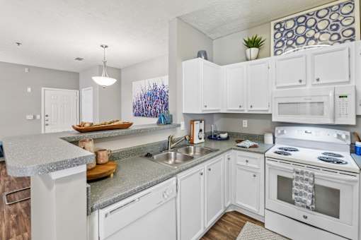 A kitchen with white cabinets and appliances.
