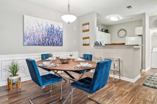 A dining room with a table set for two and a large abstract painting on the wall.