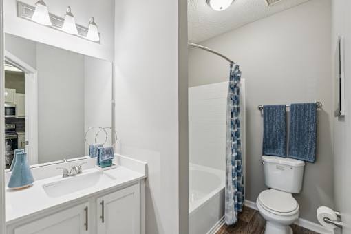 A white bathroom with a blue vase on the sink at The Atlantic Canton Ridge, Georgia