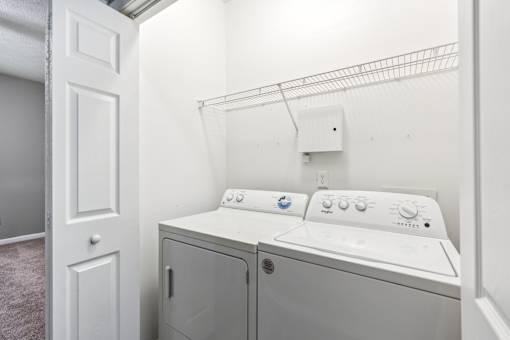 A white washer and dryer in a small laundry room at The Atlantic Canton Ridge, Georgia
