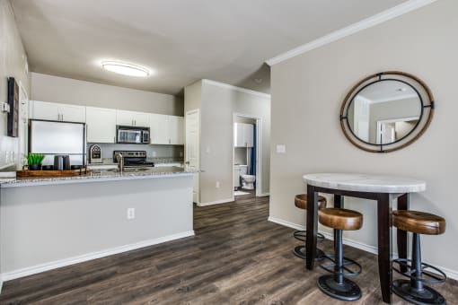 a living room with a kitchen and a bar with stools at Village of Hawks Creek Apartments, Westworth Village, TX