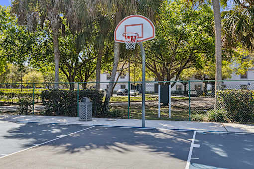 A basketball hoop is mounted on a pole in a basketball court.