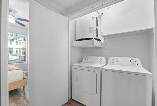 A small laundry room with a washer and dryer at The Atlantic Highland Park, Texas, 75209