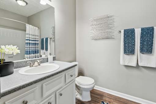 A bathroom with a white toilet, a sink, and towels hanging on the wall.
