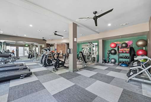 A fitness center with treadmills, exercise bikes, and weights at The Atlantic Highland Park, Texas