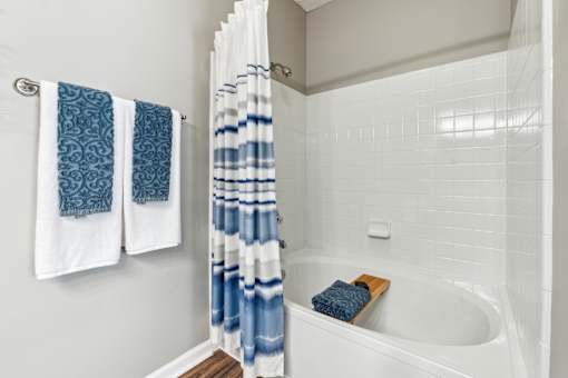 A white bathtub with a blue and white shower curtain.