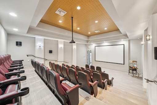 A large room with rows of red seats and a projector screen at The Atlantic at Tradition, Port St Lucie