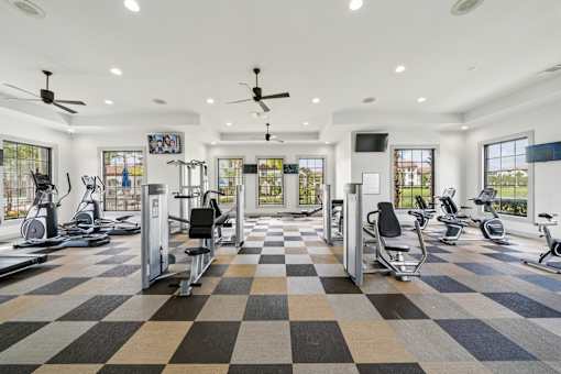 A spacious gym with a variety of exercise equipment and a checkered floor at The Atlantic at Tradition, Port St Lucie